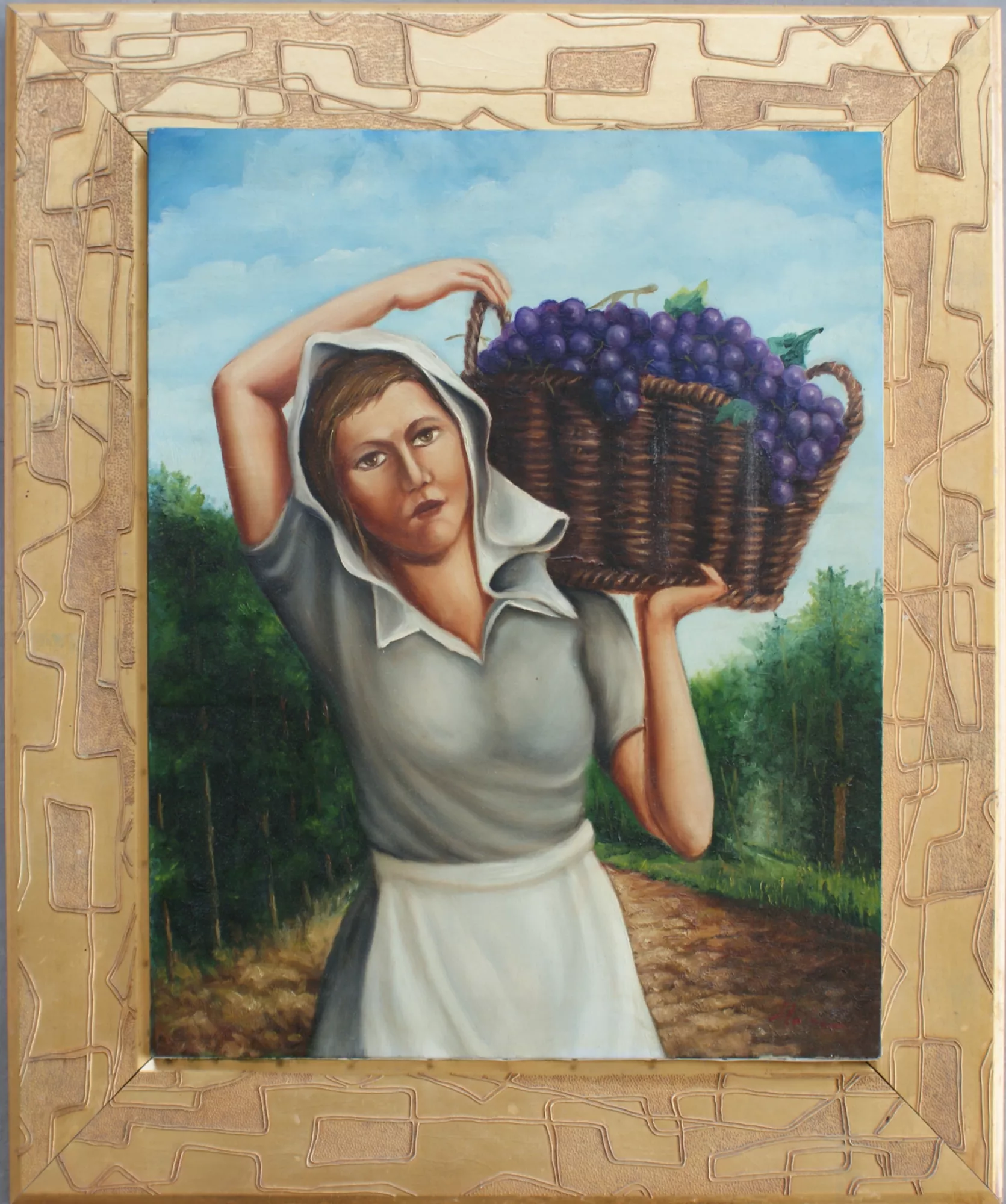 Donna-con-cesta-d'uva-Aly-Mohsen "Quadro di Ay Mohsen realizzato ad Olio con pennello. Il titolo è Donna con cesta d'uva e rientra nella categoria C'era una volta. Con Donna con cesta d’uva Aly Mohsen propone una rappresentazione rigorosa e autentica della vita rurale, inserendosi nella tradizione della pittura figurativa europea dedicata al lavoro agricolo e alla dignità del gesto quotidiano. La scena raffigura una figura femminile colta in avanzamento lungo un sentiero di campagna, mentre sostiene una cesta colma d’uva, elemento simbolico legato al ciclo naturale, alla vendemmia e alla continuità della tradizione contadina. La composizione è centrata e stabile, costruita attorno alla presenza solida della donna, che occupa lo spazio con naturalezza e misura. La postura del corpo, il peso distribuito e l’espressione composta del volto restituiscono un’immagine priva di idealizzazione, ma fortemente radicata nella realtà del lavoro rurale. Il paesaggio circostante, definito da vegetazione e luce naturale, partecipa attivamente alla costruzione narrativa, rafforzando il senso di equilibrio e autenticità. La pittura figurativa realista di Mohsen si distingue per l’attenzione alla resa anatomica, alla materia pittorica e alla qualità cromatica. La tavolozza, basata su verdi armoniosi e toni caldi, dialoga con i viola intensi dell’uva, creando un contrasto misurato e coerente che guida lo sguardo senza effetti enfatici. La luce diffusa contribuisce a un’atmosfera pacata e senza tempo. Il dipinto è accompagnato da una cornice dorata originale, sobria e finemente lavorata, che ne rafforza il carattere espositivo e museale, creando un dialogo formale tra la ricchezza dell’involucro e la semplicità del soggetto rappresentato."