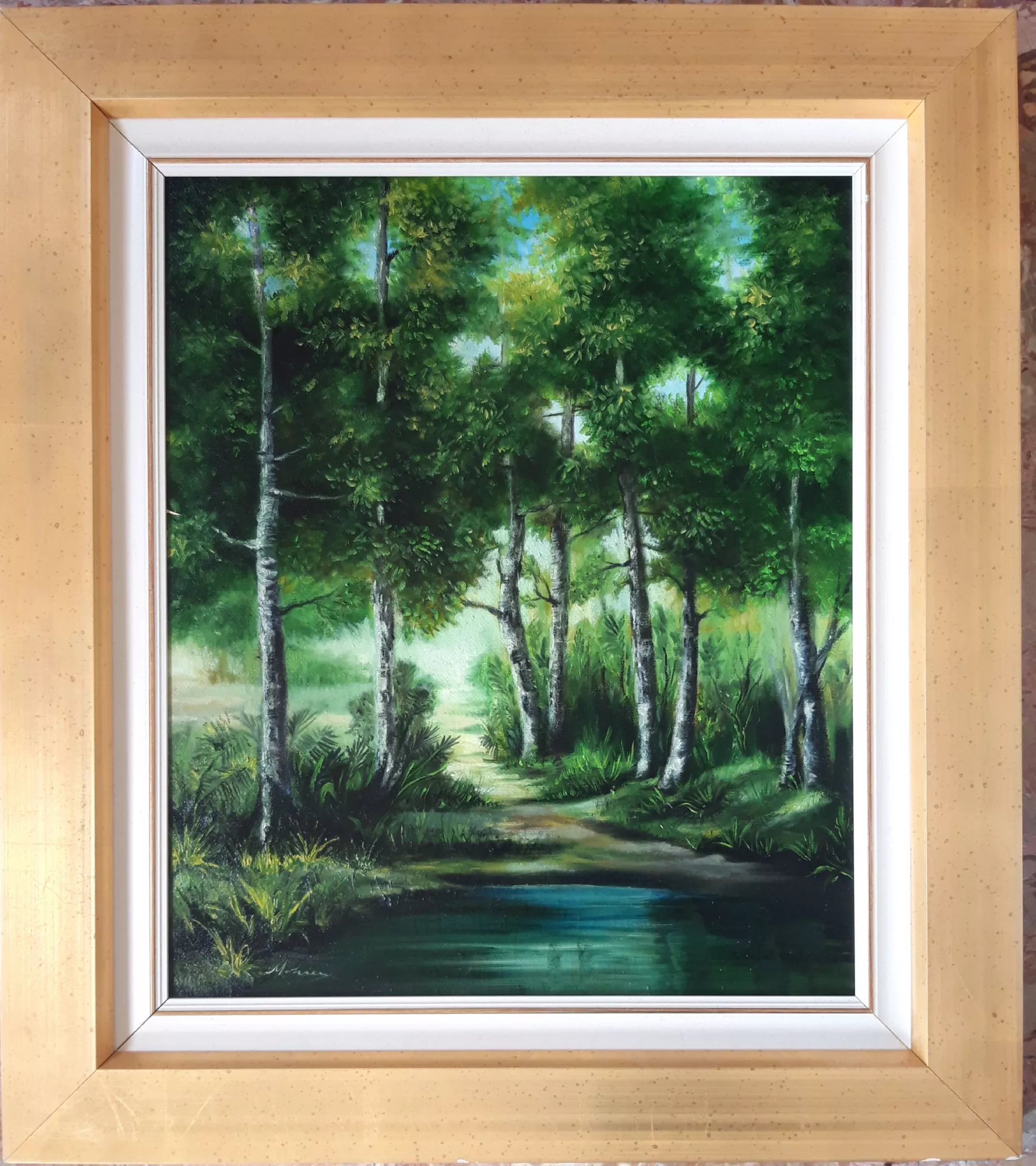 Paesaggio-con-betulle-Aly-Mohsen "Quadro di Ay Mohsen realizzato ad Olio con pennello. Il titolo è Paesaggio con betulle e rientra nella categoria Paesaggi. In Paesaggio con betulle, Aly Mohsen propone una visione naturale improntata alla quiete e all’equilibrio lirico, in cui il bosco diventa luogo di contemplazione e armonia. Le betulle, slanciate e luminose, strutturano la composizione attraverso una sequenza ritmica di verticali che accompagna lo sguardo verso il sentiero centrale, fulcro visivo e narrativo dell’opera. Il percorso, che si inoltra tra la vegetazione e conduce verso una zona più luminosa, suggerisce l’idea di un cammino silenzioso e continuo, in dialogo con la natura. In primo piano, lo specchio d’acqua riflette i verdi circostanti, introducendo una dimensione di calma e profondità che rafforza la percezione di un tempo sospeso. La pittura si sviluppa attraverso una stratificazione attenta di verdi, smeraldi e toni scuri, modulati da passaggi di luce morbidi e naturali. Le cortecce chiare delle betulle emergono con evidenza dal fondo boschivo, creando un contrasto cromatico equilibrato e una resa tattile delle superfici. La luce filtra tra le chiome in modo diffuso, senza accenti drammatici, contribuendo a un’atmosfera serena e avvolgente. La pennellata di Mohsen è fluida e controllata, capace di suggerire il movimento lieve del fogliame e la trasparenza dell’acqua, mantenendo un equilibrio costante tra descrizione figurativa e sensibilità poetica. La composizione, stabile e calibrata, invita l’osservatore a un’esperienza visiva immersiva e raccolta. La cornice chiara, essenziale e luminosa, accompagna l’opera con discrezione, valorizzandone la freschezza cromatica e rafforzando il carattere contemplativo dell’insieme. Paesaggio con betulle si colloca coerentemente nella produzione di Aly Mohsen dedicata al paesaggio figurativo come spazio di silenzio, equilibrio e relazione profonda con l’ambiente naturale."