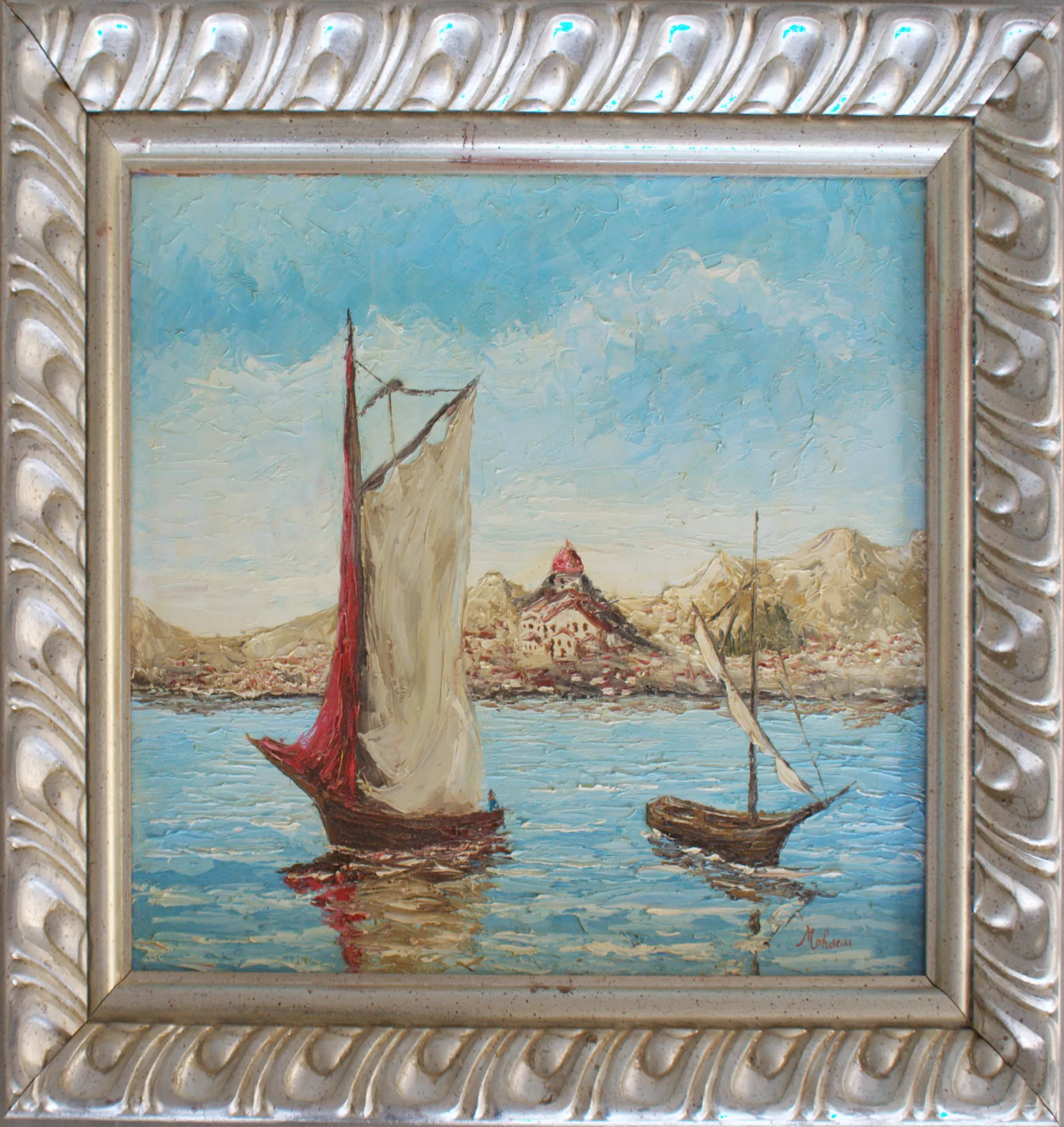 Barche-con-Sanremo-sullo-sfondo-Aly-Mohsen "Quadro di Ay Mohsen realizzato ad Olio con spatola. Il titolo è Barche con Sanremo sullo sfondo e rientra nella categoria Il mare. Opera originale di Aly Mohsen raffigurante un paesaggio marino con barche a vela e Sanremo sullo sfondo, chiaro riferimento alla Riviera ligure, territorio profondamente legato alla ricerca pittorica dell’artista. Il dipinto è realizzato a olio su tela con tecnica a spatola, cifra stilistica distintiva di Mohsen, che conferisce alla superficie pittorica una forte matericità e una resa luminosa intensa e vibrante. In primo piano, due imbarcazioni tradizionali solcano un mare calmo e riflettente: la barca principale, con vela chiara affiancata da una vela rossa, domina la composizione e cattura immediatamente lo sguardo, mentre una seconda barca più piccola, leggermente arretrata, introduce equilibrio visivo e profondità prospettica. Le spatolate dense e dinamiche costruiscono l’acqua attraverso riflessi e leggere increspature, mentre il cielo azzurro, lavorato con ampie campiture materiche, amplifica la sensazione di spazio e apertura. Sul fondo emerge il profilo urbano di Sanremo, riconoscibile dal santuario con cupola centrale adagiato tra le colline. Questo elemento architettonico arricchisce la scena di valore narrativo e territoriale, creando un dialogo armonioso tra il paesaggio marino, le barche e l’identità storica del luogo. L’insieme restituisce una visione equilibrata e senza tempo del Mediterraneo. L’opera è completata da una cornice argentata finemente lavorata, caratterizzata da motivi classici in rilievo che incorniciano il dipinto con eleganza e sobrietà. La cornice dialoga armoniosamente con i toni dell’opera, valorizzandone la luminosità e la forza espressiva, rendendo il lavoro immediatamente pronto per l’esposizione in ambienti raffinati e collezioni private."