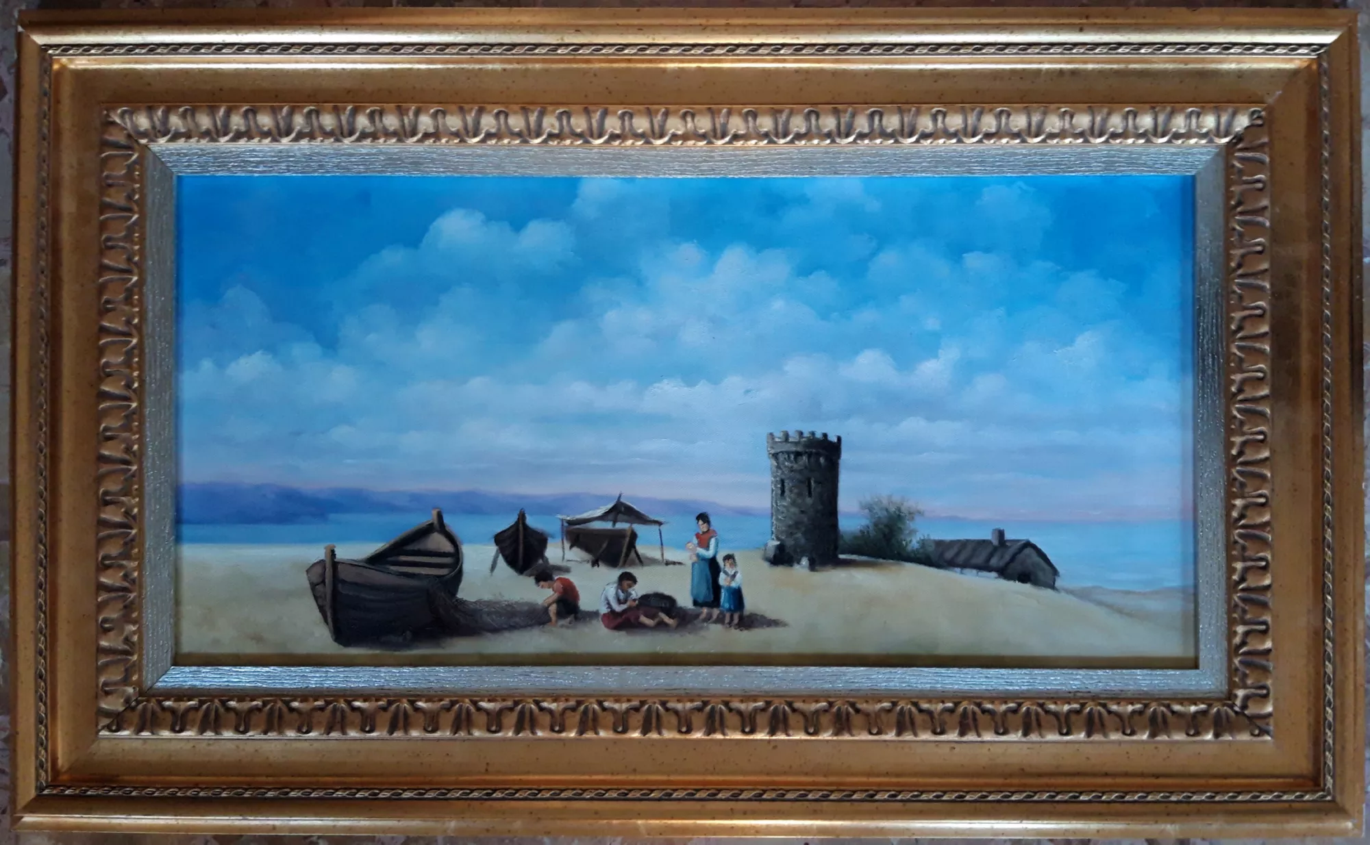 Famiglia-del-pescatore-in-spiaggia-Aly-Mohsen "Quadro di Ay Mohsen realizzato ad Olio con pennello. Il titolo è Famiglia del pescatore in spiaggia e rientra nella categoria Il mare. Opera originale di Aly Mohsen che raffigura una scena di vita quotidiana sulla spiaggia, offrendo una lettura pacata e poetica del mondo dei pescatori e delle loro famiglie. La composizione si caratterizza per un impianto narrativo equilibrato e per un linguaggio figurativo misurato, attraverso il quale l’artista restituisce un momento di quiete legato alla dimensione domestica e comunitaria della vita costiera. Al centro della scena è rappresentato un gruppo familiare raccolto sulla sabbia, colto in un momento di pausa e condivisione. Le figure, dipinte con attenzione ai gesti e alle relazioni reciproche, trasmettono un senso di armonia e continuità, suggerendo il legame profondo tra lavoro, affetti e ambiente marino. Bambini e adulti sono inseriti con naturalezza nello spazio, diventando parte integrante del paesaggio e del racconto visivo. Sullo sfondo si distinguono le barche da pesca tirate in secca, una torre costiera in pietra e alcune strutture essenziali del borgo marinaro, elementi che conferiscono alla scena una precisa collocazione territoriale riconducibile al paesaggio della Riviera ligure e più in generale alla tradizione mediterranea. Il mare calmo e l’orizzonte ampio ampliano la profondità spaziale, mentre il cielo, esteso e luminoso, è costruito con morbide sfumature di azzurro e bianco ottenute tramite una pittura controllata e priva di effetti materici accentuati. La luce diffusa e uniforme avvolge l’intera composizione, creando un’atmosfera di stabilità e serenità che si pone in dialogo con le marine più drammatiche dell’artista. In quest’opera Aly Mohsen privilegia una narrazione silenziosa, fondata su valori di continuità, tradizione e quotidianità, elementi ricorrenti nella sua ricerca figurativa. Il dipinto è completato da una cornice di gusto classico, con finitura dorata e decorazioni in rilievo. Il bordo interno argentato introduce un contrasto cromatico equilibrato che accompagna lo sguardo verso la scena centrale, valorizzando i toni del cielo e della spiaggia e conferendo all’opera una presenza visiva armoniosa e compiuta."
