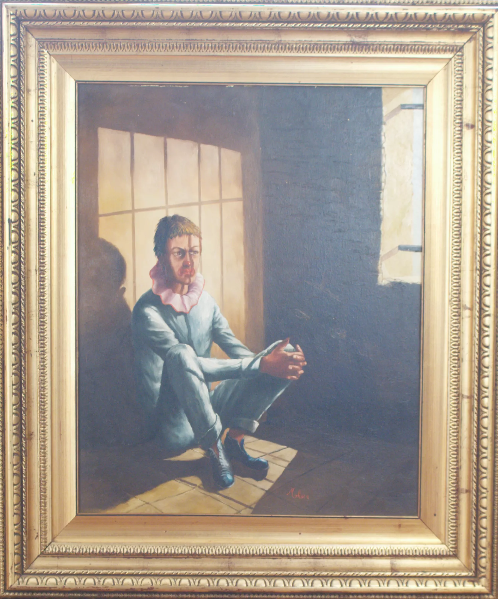 La-frustrazione-Aly-Mohsen "Quadro di Ay Mohsen realizzato ad Olio con pennello. Il titolo è La frustrazione e rientra nella categoria La vita e l'arte. La Frustrazione è un’opera di forte impatto simbolico e sociale in cui Aly Mohsen affronta il tema universale della malagiustizia e della sofferenza interiore. Il dipinto raffigura un pagliaccio seduto in una cella spoglia, isolato nello spazio e nel silenzio, colto in una posa raccolta che accentua il peso psicologico della prigionia. Elemento centrale della composizione è la luce che filtra dalla finestra, proiettando sul volto del pagliaccio l’ombra delle sbarre: un potente gioco chiaroscurale che diventa metafora visiva della condizione umana sospesa tra costrizione e speranza. La scelta del pagliaccio, figura tradizionalmente legata al sorriso e all’intrattenimento, amplifica il contrasto emotivo dell’opera: chi dovrebbe portare gioia è qui vittima di un’ingiustizia profonda. Nell’espressione del volto si concentrano tristezza, rabbia e determinazione, restituendo una narrazione intensa e senza tempo. L’opera è dedicata a tutte le vittime di ingiusta detenzione e si inserisce nella produzione più concettuale e impegnata dell’artista, rendendola di particolare interesse per collezionisti e investitori attenti all’arte contemporanea a contenuto etico e simbolico. La luce assume un valore ulteriore: rappresenta la verità e la speranza che essa possa emergere, conducendo allo scagionamento e alla redenzione. Dal punto di vista tecnico, l’opera mostra una stesura pittorica misurata, con un uso del pennello che alterna superfici compatte a passaggi più morbidi e sfumati. La resa dei materiali — pelle, tessuto, muratura e pavimentazione — è affidata a variazioni tonali e a una gestione attenta della materia pittorica, funzionale alla chiarezza formale e narrativa. La cornice, in legno con finitura dorata e modanature decorative di gusto classico, definisce il perimetro dell’opera e ne stabilizza la lettura visiva, separando lo spazio rappresentato dall’ambiente esterno e conferendo all’immagine un assetto concluso e autonomo."