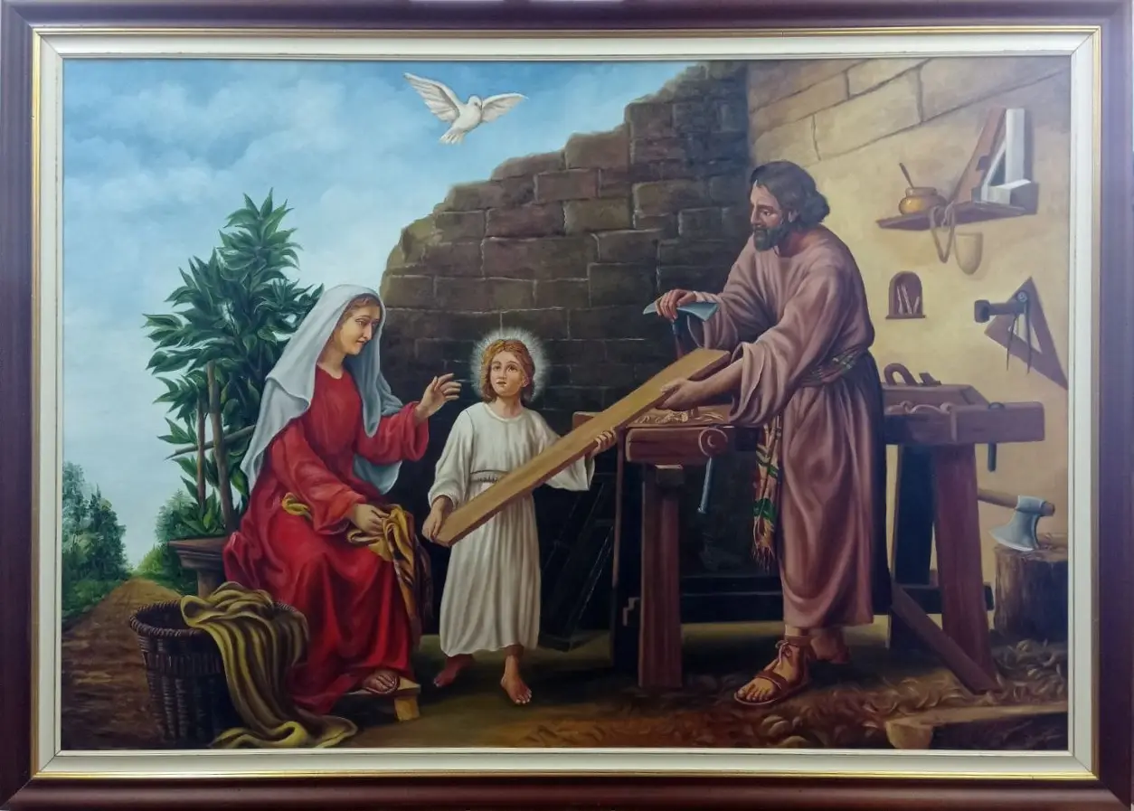San-Giuseppe-falegname-Aly-Mohsen "Quadro di Ay Mohsen realizzato ad Olio con pennello. Il titolo è San Giuseppe falegname e rientra nella categoria Arte Sacra. Con San Giuseppe falegname Aly Mohsen affronta uno dei temi più alti e complessi della tradizione iconografica cristiana, restituendolo attraverso una narrazione figurativa equilibrata, di forte impatto simbolico e profonda umanità. L’opera propone una visione intima e monumentale insieme, in cui il sacro si manifesta nella dimensione quotidiana del lavoro, della famiglia e dell’educazione. Al centro della composizione, il giovane Gesù partecipa all’attività del padre, reggendo una tavola di legno appena lavorata. Il gesto semplice del lavoro condiviso assume valore simbolico, evocando la trasmissione del sapere, la formazione morale e la preparazione al destino futuro. La figura della Madonna, posta lateralmente, introduce una dimensione di protezione e ascolto: il suo atteggiamento raccolto e vigile contribuisce all’equilibrio affettivo e spirituale della scena. San Giuseppe è rappresentato come uomo del lavoro, solido e concentrato, privo di idealizzazioni retoriche. Gli strumenti del mestiere, il banco, il legno grezzo e le superfici murarie definiscono un ambiente credibile e concreto, in cui il lavoro manuale assume un significato etico e sacrale. La colomba, collocata nello spazio superiore, richiama con discrezione la presenza divina, senza interrompere la naturalezza narrativa dell’insieme. La composizione è ampia e rigorosa, costruita su un equilibrio triangolare che garantisce stabilità visiva e profondità simbolica. La luce diffusa modella le figure con dolcezza, mentre la tavolozza, dominata da ocra, bruni caldi, azzurri e rossi attenuati, contribuisce a creare un’atmosfera di armonia e tempo sospeso. La pittura figurativa di Aly Mohsen si distingue per la precisione anatomica, la cura dei dettagli e la resa materica del legno e dei tessuti, elementi che conferiscono all’opera una forte presenza visiva e una leggibilità efficace anche a distanza. Il dipinto è completato da una cornice in legno con finitura scura e profilo interno dorato, caratterizzata da un disegno essenziale di gusto classico. La cornice definisce con equilibrio lo spazio dell'immagine, valorizza la gamma cromatica dell'opera e ne rafforza la presenza visiva, accompagnando la narrazione senza interferire con la lettura della scena sacra. Opera figurativa originale di Aly Mohsen, San Giuseppe falegname si inserisce nel ciclo dedicato alla pittura religiosa e narrativa, riletta con sensibilità contemporanea e solida impostazione tecnica."